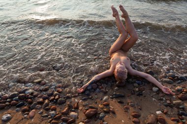 Yaşam tarzı ve güzellik konsepti. Güzel çıplak kadın doğanın tadını çıkarıyor. Deniz kıyısında seksi çıplak kadın.