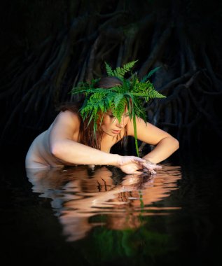 Sakin bir orman nehrinde, genç bir kadın başındaki eğreltiotu çelengiyle çıplak poz verir, zarif bir şekilde suyla etkileşir. Doğa, etrafındaki sükuneti kucaklarken onu da sarar..