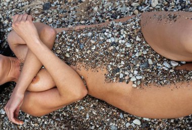 Çıplak bir kadın çakıl taşlarından oluşan bir yatakta huzur içinde yatıyor. Vücudu kısmen küçük taşlar ve kumla kaplı. Doğayla olan bağını, sakin bir ortamda somutlaştırıyor..