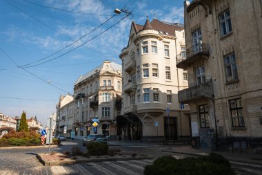 Lviv, Ukrayna - Mar. 22, 2025: Tuhaf binalar Lviv 'in sakin caddelerini kaplıyor, parlak mavi gökyüzü altında büyüleyici mimari tarzlar sergiliyor. Barışçıl bir atmosfer keşfi davet eder.