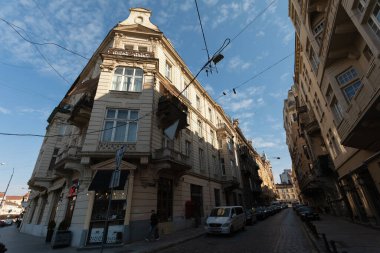 Lviv, Ukrayna - Mar. 22, 2025: Muhteşem mimari, Ukrayna 'nın Lviv kentinin kaldırım taşlı sokaklarında, sakinler mavi gökyüzü ve yumuşak bulutların altında güzel bir günün tadını çıkarırken,.