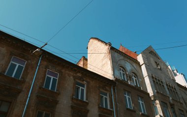 Lviv, Ukrayna - Mar. 22, 2025: Lviv, Ukrayna 'da kendine has mimari tarzları ve kentsel yaşamın cazibesini sergileyen parlak mavi gökyüzüne karşı ayırt edici binalar yükselir..