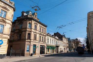 Lviv, Ukrayna - Mar. 22, 2025: Lvivs 'in tarihi bölgesinde dolaşmak, eski binalar caddelerde dizilmiş, parlak mavi gökyüzü altında çarpıcı bir mimari sergiliyor..