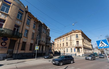 Lviv, Ukrayna - Mar. 22, 2025: Tarihi binaların modern arabaların yanında durduğu Lvivlerin hareketli sokaklarına bir göz atın, açık mavi gökyüzü altında şehirlerin zamansız cazibesini sergiliyorlar..