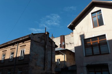 Lviv, Ukrayna - Mar. 22, 2025: Kırsal cepheli eski binalar Lviv 'deki modern yapılara karşıdır. Parlak güneş ışığı farklı gölgeler bırakır ve şehirde canlı bir atmosfer yaratır..