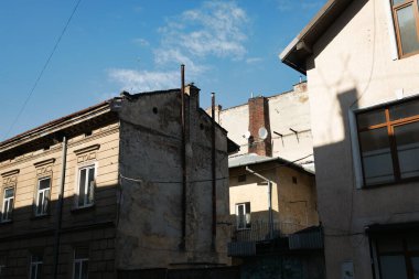 Lviv, Ukrayna - Mar. 22, 2025: Güneş ışığı Lviv 'in tarihi binalarına gölge düşürüyor, mimari ayrıntıları ve dokuları vurguluyor. Açık mavi bir gökyüzü bu şehir manzarasını tamamlıyor.