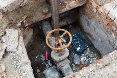Paslı bir vana ve atılmış bir çöp yığını tuğla ve betonla çevrili bir çukurda oturur. Şehir ortamında ihmal ve bakımsızlığı gösterir..
