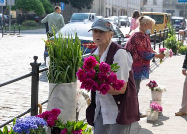 LVIV, UKRAINE - Haziran. 20, 2021: Sokak satıcıları hareketli kaldırım boyunca renkli çiçek buketleri düzenler ve satarlar. Yerel halk, şehrin hareketli atmosferinin tadını çıkararak geziniyor..
