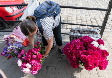 LVIV, UKRAINE - Haziran. 20, 2021: Sokak satıcıları tezgahlarıyla ilgilenirken renkli çiçek düzenlemeleri sergiliyorlar. Buranın yerlileri çiçeklerin tadını çıkarırken atmosfer hareketli..