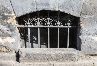 LVIV, UKRAINE - Haziran. 20, 2021: Karmaşık demir ızgaralar Lviv 'in tarihsel bölümündeki yıpranmış taş bir pencereyi kaplıyor, şehirlerin eşsiz cazibesini ve zengin mimari mirasını vurguluyor..