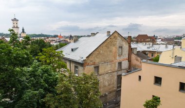 LVIV, UKRAINE - Haziran. 20, 2021: Lviv 'deki tarihi mimarinin eski binaları ve çatıları gösteren görüntüsü. Yeşillik, şehir manzarasıyla çelişiyor ve şehrin özünü yakalıyor..