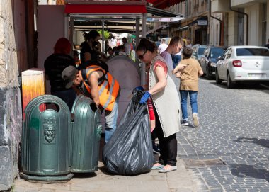 LVIV, UKRAINE - Haziran. 20, 2021: Yerel gönüllüler kalabalık bir alanda çöp topluyor, halkın temizliğin korunmasına katılmasını teşvik ediyor, insanlar gelip günün tadını çıkarıyor.