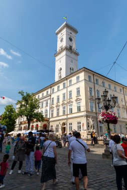 LVIV, UKRAINE - Haziran. 20, 2021: Yerel halk ve ziyaretçiler sıcak bir günde canlı atmosferi ve güzel mimariyi alarak Lviv 'in büyüleyici sokaklarında geziniyorlar..