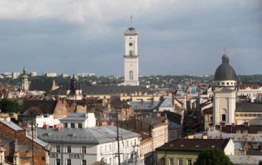 LVIV, UKRAINE - Haziran. 20, 2021: Lviv 'in ufuk çizgisi tarihi binaların bir karışımını sergiliyor, önemli belediye binası kulesi resim gibi çatılar ve zarif kubbeler arasında dikiliyor..