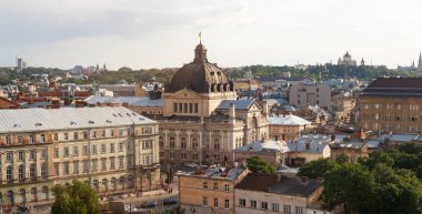 LVIV, UKRAINE - Haziran. 20, 2021: Lviv 'in eşsiz çatılarına ve tarihi binalarına bakan, parçalı bulutlu bir gökyüzü altında karmaşık mimari ve canlı şehir yaşamını gözler önüne seren,.