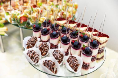 Katmanlı parfümler, pasta dilimleri ve hamur işleri de dahil olmak üzere cam bir yüzeye çeşitli minyatür tatlılar yerleştirilir..