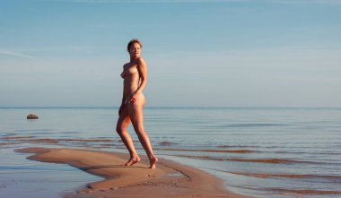 Rasta saçlı genç bir kadın güneşli bir yaz öğleden sonrasında deniz kenarında çıplak poz veriyor. Güzellik ve sağlıklı yaşam tarzı kavramı. 