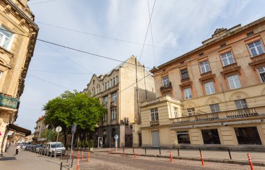 Lviv, Ukrayna - Haziran. 01, 2025: Ukrayna 'nın Lviv şehrinde tarihi binalar ve park edilmiş arabalarla dolu bir sokak sahnesi.