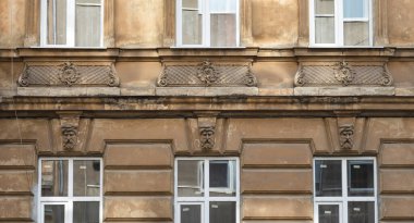 Lviv, Ukrayna - Haziran. 01, 2025: Pencereleri ve dekoratif mimari detayları olan eski bir binanın cephesi.