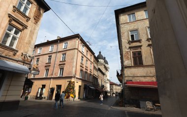 Lviv, Ukrayna - Haziran. 01, 2025: Lviv 'de tarihi bir caddenin aşağısında, eski binalar ve gezinen insanlarla dolu bir manzara.