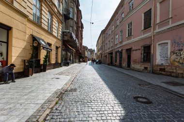 Lviv, Ukrayna - Haziran. 01, 2025: Açık bir gökyüzü altında mimari tarzların bir karışımını sergileyen tarihi binalarla dolu bir kaldırım taşı caddesi.