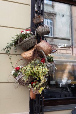Lviv, Ukrayna - Haziran. Wicker sepetleri canlı çiçekler ve gür yeşilliklerle dolu bir binanın dış yüzünü süslüyor..
