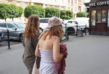 Lviv, Ukrayna - Haziran. 01, 2025: Bir caddede yürüyen iki kadın, biri türban takıyor.