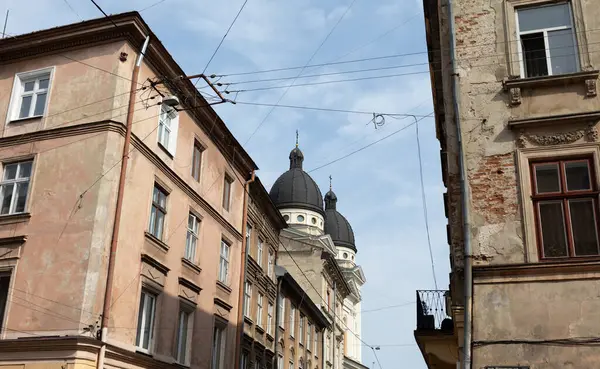 Lviv, Ukrayna - Haziran. 01, 2025: Eski binaların mimari güzelliklerini ve temiz gökyüzüne karşı bir kilisenin ikonik kubbelerini gösteren bir sokak görüntüsü.