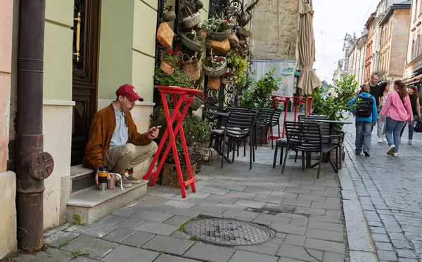 Lviv, Ukrayna - Haziran. 01, 2025: Şapka takan bir adam bir kafenin merdivenlerinde oturuyor.