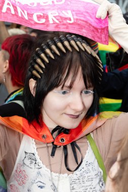 Kyiv, Ukrayna - Haziran. 14, 2025: Göz alıcı makyajlı ve başlıklı genç bir kadın KyivvPride geçit törenine katılıyor.