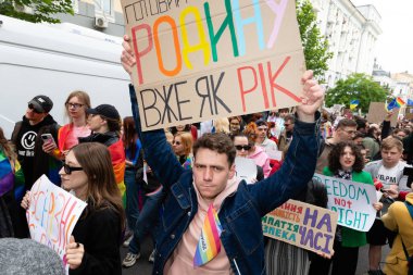 Kyiv, Ukrayna - Haziran. 14, 2025: KyivPride sırasında bir gösterici, diğer protestocular ve LGBTQ + haklarını destekleyen pankartlarla çevrili bir tabela tutuyor.