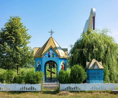 Teresva, Transcarpathia 'da, yeşilliklerin arasına gizlenmiş büyüleyici bir şapel görülüyor. Yakınlarda bir leylek görülüyor ve bu huzurlu yerin huzurlu atmosferine bir kuyu ekleniyor..