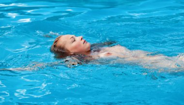 Genç çıplak bir kadın havuzda dinleniyor..