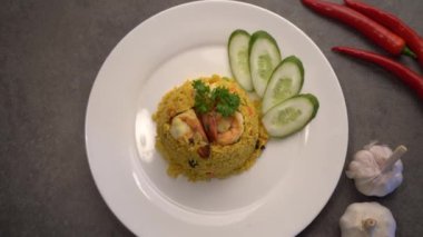 Beyaz tabakta karides ve körili Tayland baharatlı pilavı.