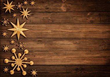 Christmas Wooden Background with Golden Stars and Snowflakes. Xmas Ornament Design on brown Wood Table with Copy Space