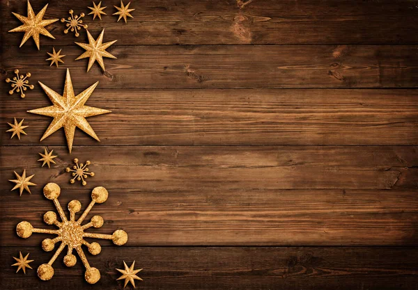 Christmas Wooden Background with Golden Stars and Snowflakes. Xmas Ornament Design on brown Wood Table with Copy Space