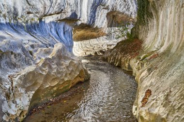 Kayalık bir kanyonu ve kireçtaşı dağlarında bir nehri olan bir manzara.