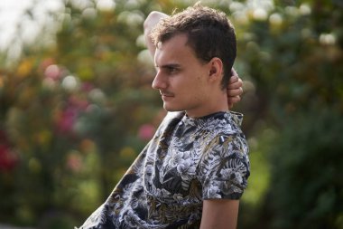 Kırsalda güneşli bir günde bahçesinde dinlenen genç bir adam.