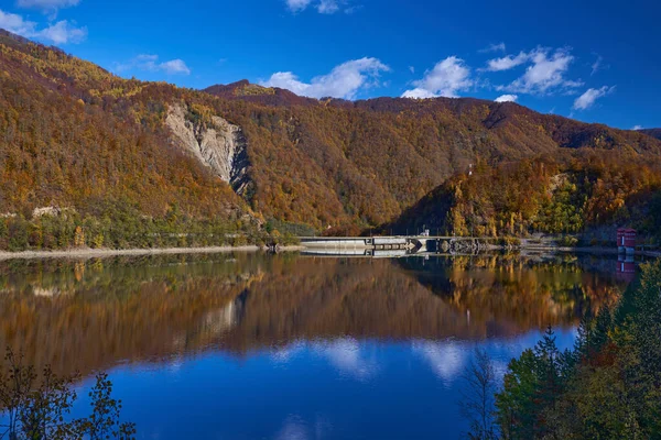 ダム湖を囲む山の上のカラフルな森と水の中の反射 — ストック写真