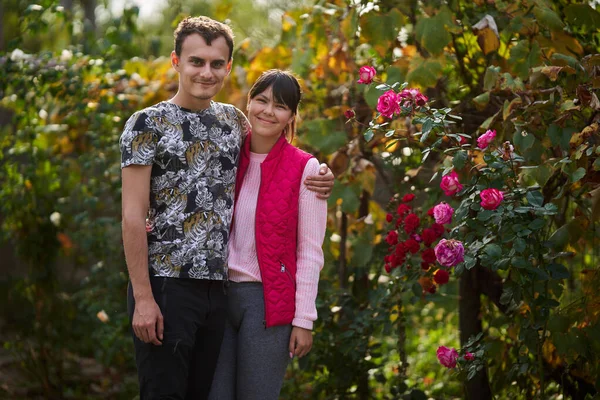 一对快乐的年轻夫妇在他们乡间的玫瑰花园里安坐着 — 图库照片