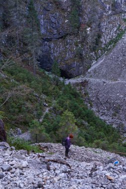 Sırt çantalı bir kadın dağda yürüyüş parkurunda yürüyor.