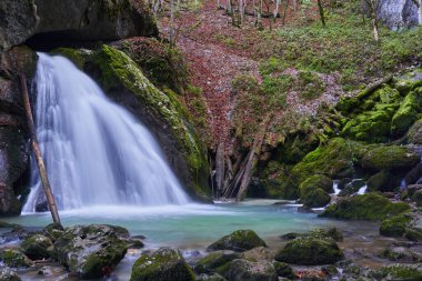 Lüks bir kanyonda şelale yosun ve masmavi sularla dolu yemyeşil bir bitki örtüsüyle kaplı.