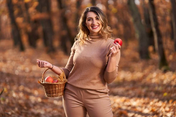 在橡木林里 还有一个身材魁梧的美丽女人 带着一篮子苹果野餐 — 图库照片