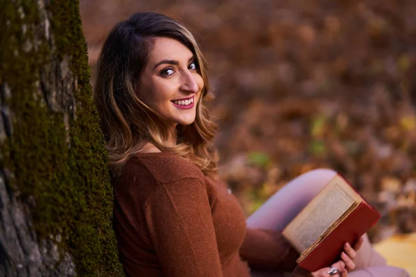 秋の終わりに森の中で本を読んでいる若い女性 — ストック写真