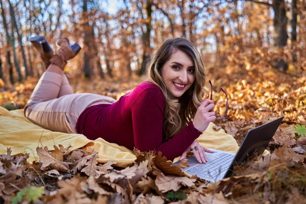 年轻的女商人一边在笔记本电脑上工作 一边在森林里享受美丽的秋天 — 图库照片