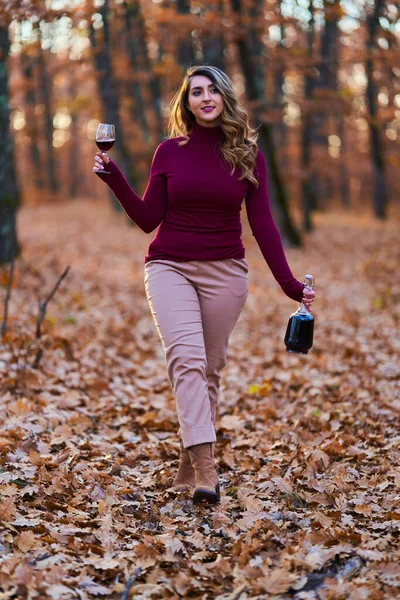 美しいプラスサイズの若いインド人女性が日没時にオークの森の中で赤ワインを楽しんでいます — ストック写真