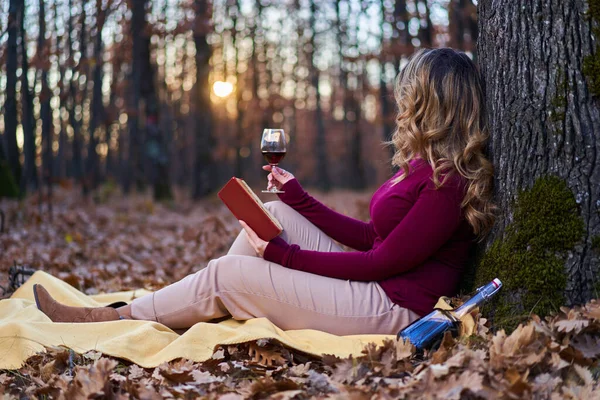 日落时分 美丽又大的印度年轻女子在橡木森林里品着一杯红酒和一本书 — 图库照片