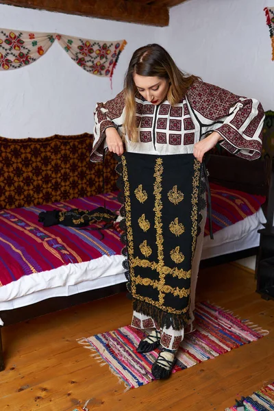 伝統的な農村の家で伝統的な人気の衣装を着た若いルーマニアの女性 — ストック写真