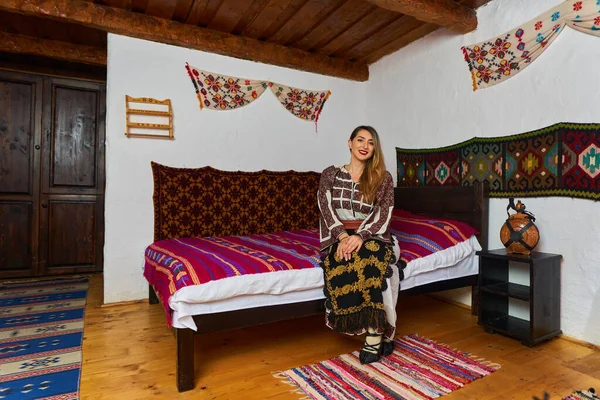 伝統的な農村の家で伝統的な人気の衣装を着た若いルーマニアの女性 — ストック写真