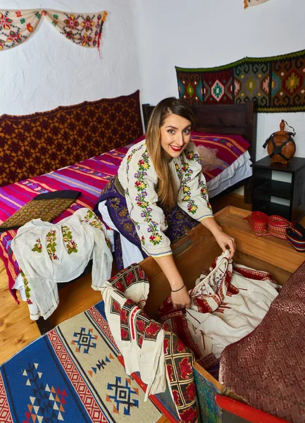 Молодая Румынская Женщина Открывает Свадебный Сундук Многими Традиционными Костюмами Примерить — стоковое фото